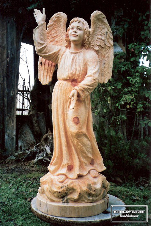 Ein Engel aus Holz der mit der rechten Hand in den Himmel zeigt