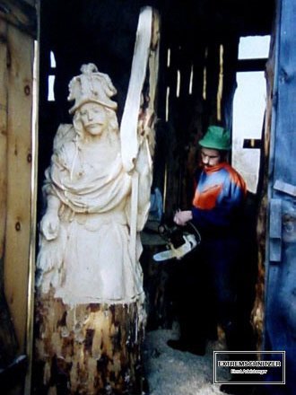 Ernst Adelsberger bei der Arbeit mit der Motorsäge. Er ist gerade dabei, den heiligen Florian aus einem Baumstamm auszuschnitzen.