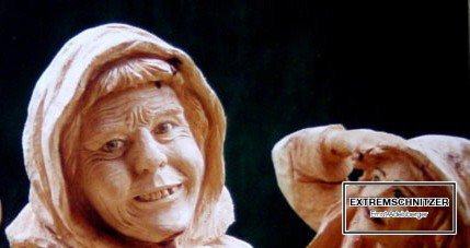 Eine lächelnde alte Frau mit Kopftuch als Porträtfigur aus Holz.
